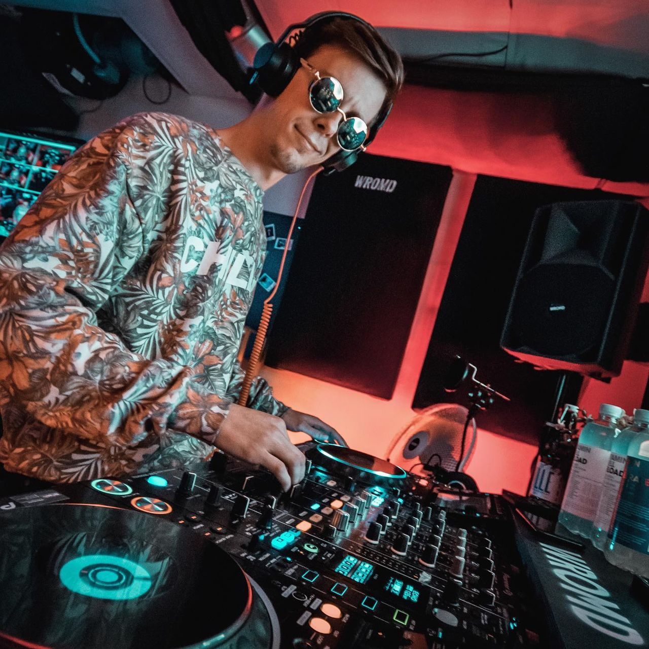3LTON kõrvaklappidega DJ-puldi taga punases ja sinises valguses.